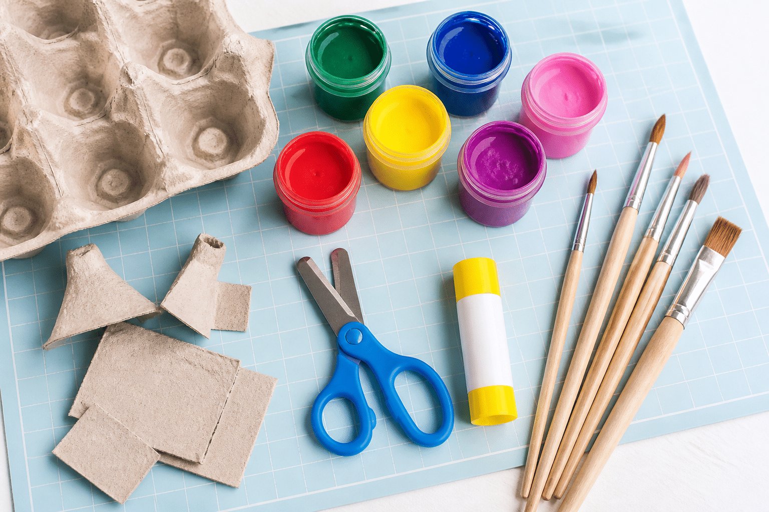 Kindersichere Schere, Pinsel und Farben bereitgestellt für das Basteln mit Eierkartons